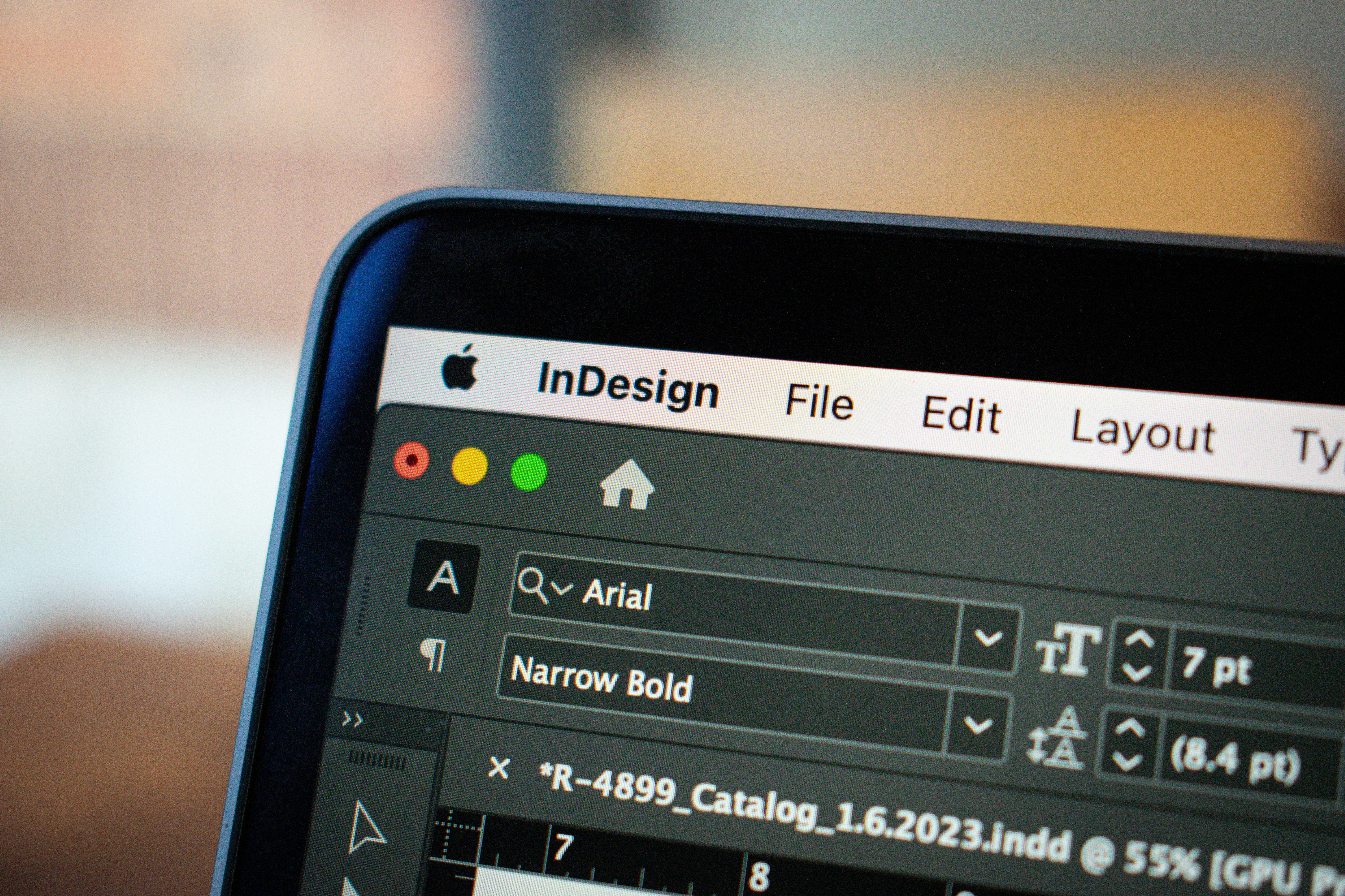 Close-up of Adobe InDesign running on a laptop, showing typography controls and a publication layout in progress