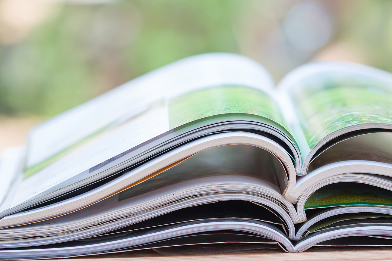 A stack of printed open reports and publications with soft out of focus background
